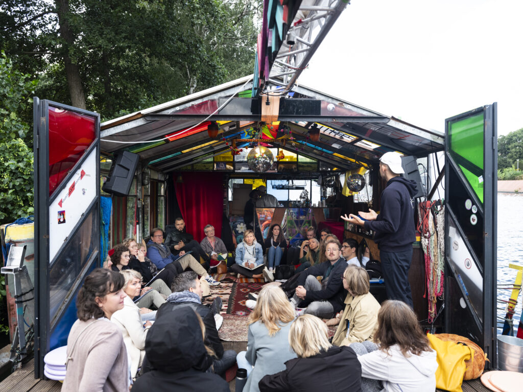 Thomas facilitating a group conversation on a boat at Balance Festival